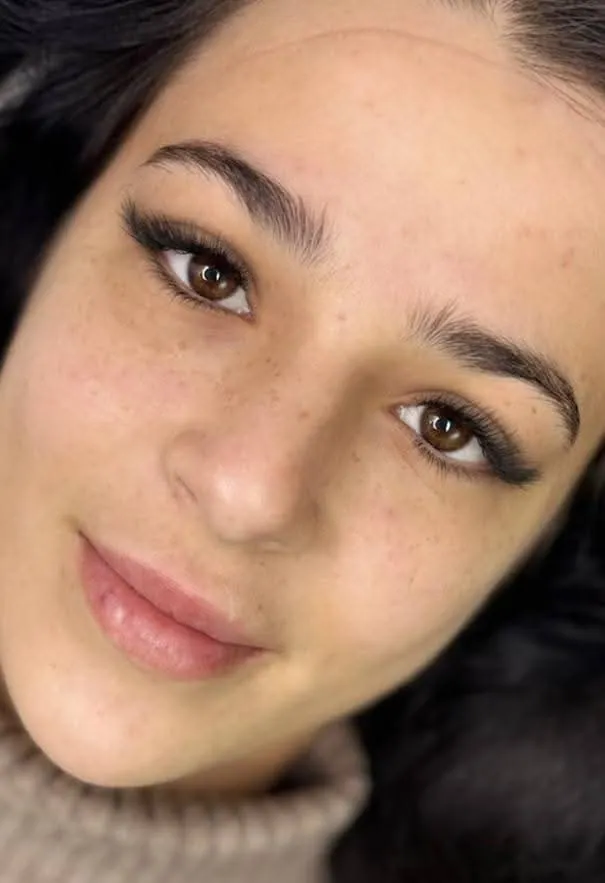 Cliente châtain en pull gris avec extensions de cils